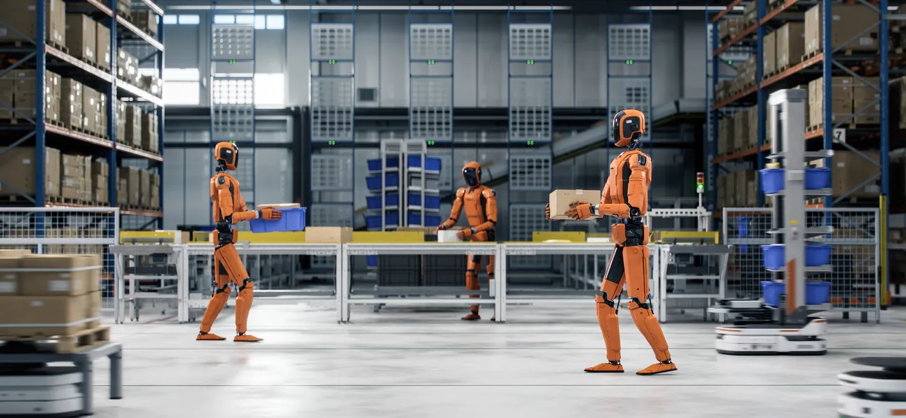 Orange humanoid robots carrying totes and boxes through a warehouse fulfilment centre