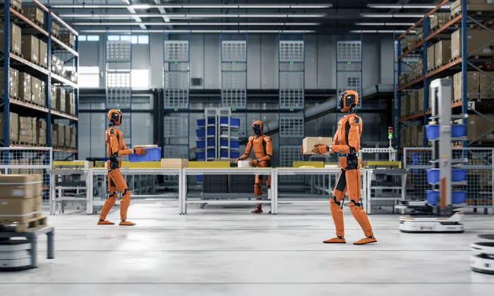 Orange humanoid robots carrying totes and boxes through a warehouse fulfilment centre